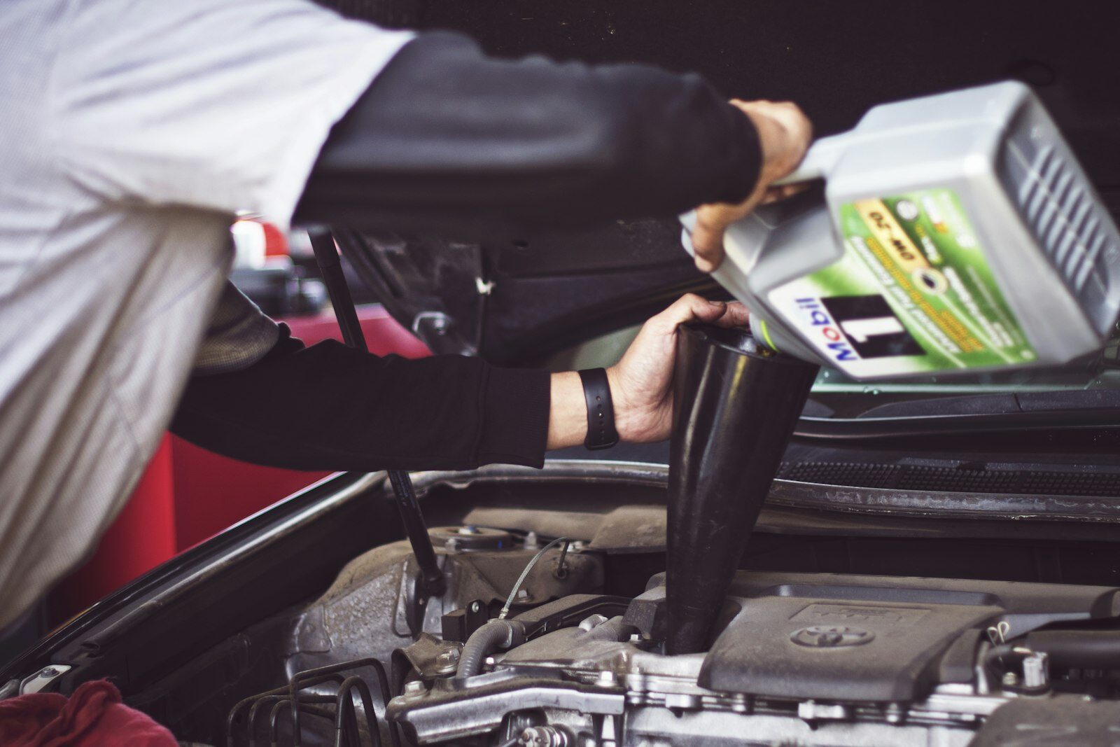 Ölwechsel & KFZ-Service 1230 Wien – Motoröl nachfüllen Mechaniker füllt beim Ölwechsel frisches Motoröl in den Motor