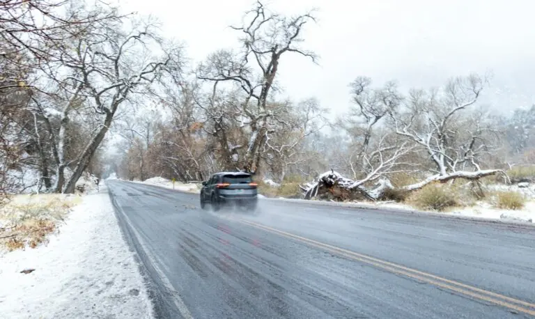 Auto im Winter auf nasser Straße mit Schnee am Rand: Zeit, das Auto winterfit zu machen